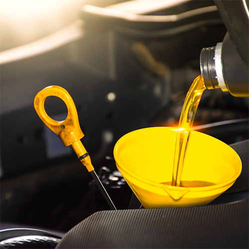 New oil being poured into a yellow funnel during an oil change in Seminole