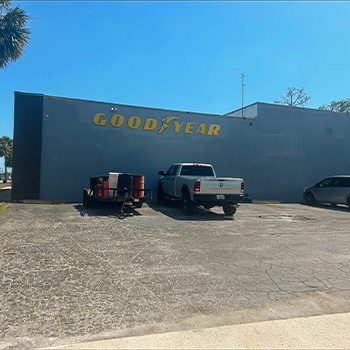 Two cars parked in the Goodyear tires tire and auto repair service parking lot.