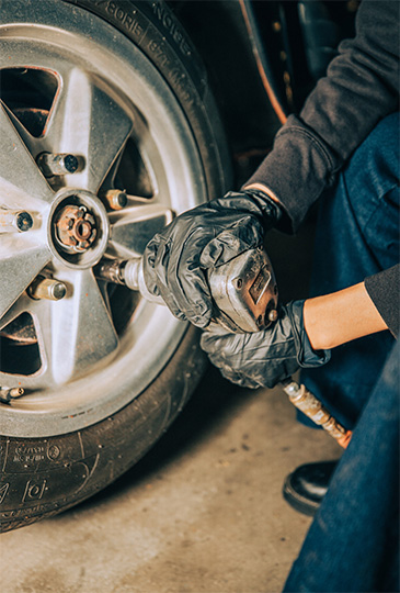 Gloved hands perform a tire replacement on an old tire