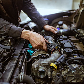 Mechanic hands touching the engine of an open car hood during a tune-up