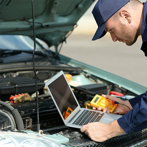 A mechanic uses a laptop to diagnose electrical repair services needed in Seminole