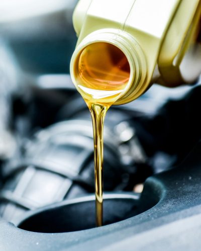 New oil is poured from a golden bottle during an oil change